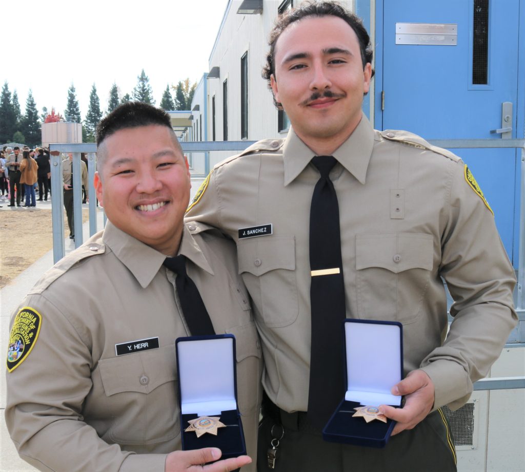 Two cadets hold badges at the academy after graduation.
