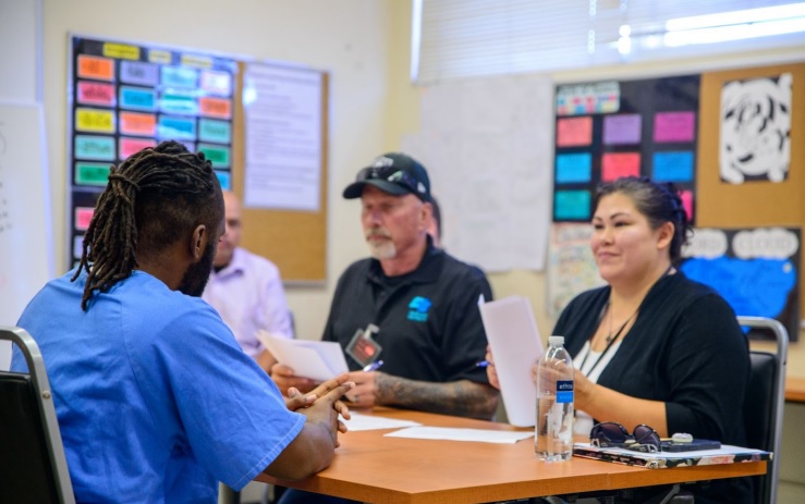 Two people interview an incarcerated job seeker at a hiring workshop.