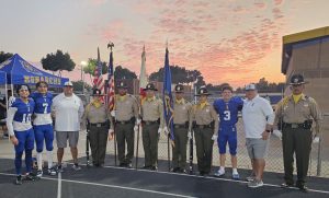 Honor Guard with high school football players and coaches before a game to honor first responders and military.