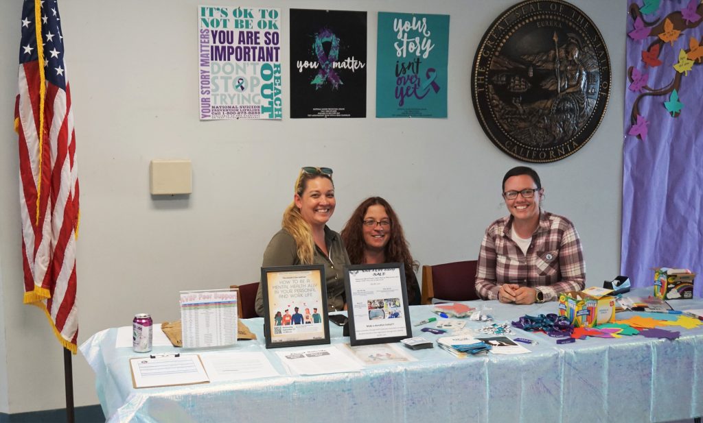 Three Kern Valley State Prison mental health staff at a suicide prevention awareness table.