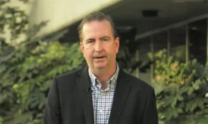 CDCR Secretary Macomber stands in an atrium at headquarters for a holiday video message.