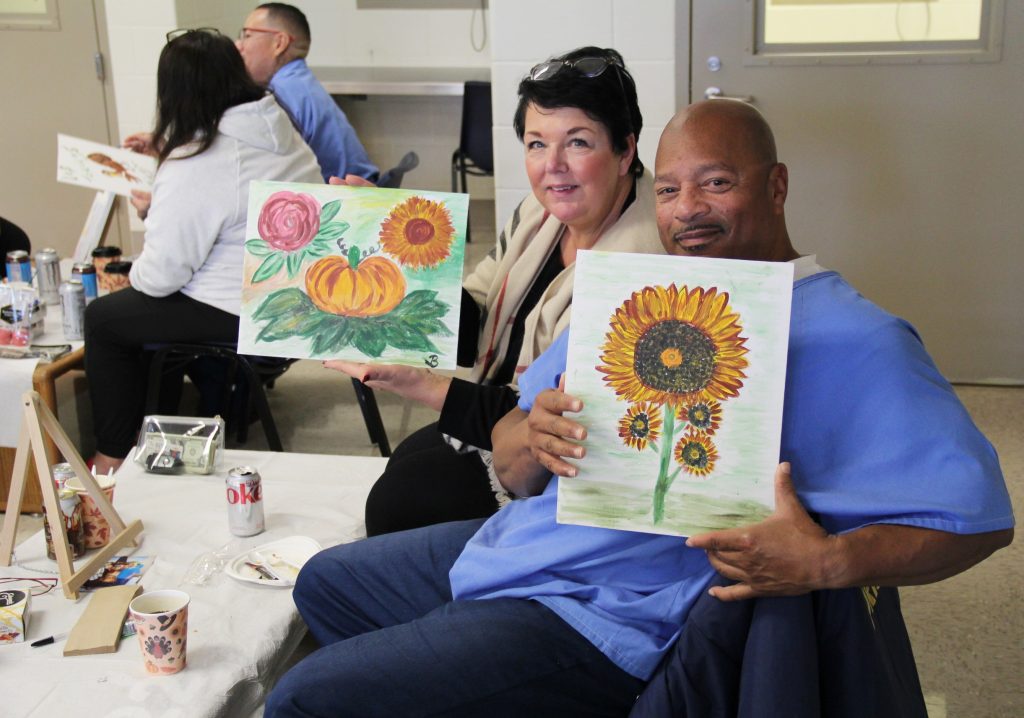 People hold up their paintings at California Health Care Facility for Thanksgiving visiting.