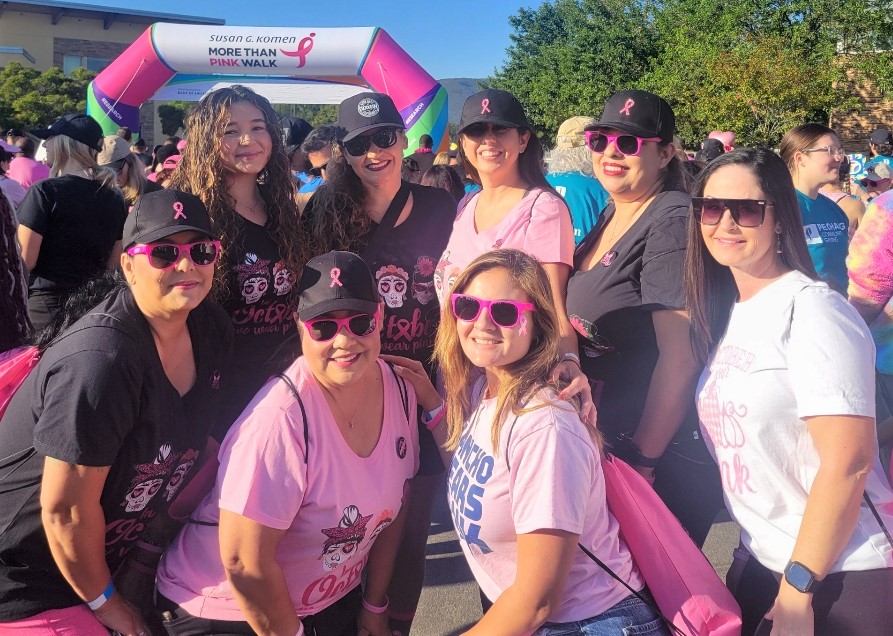 California Institution for Men staff wearing pink and standing beside a large inflatable start line for a breast cancer awareness walk.