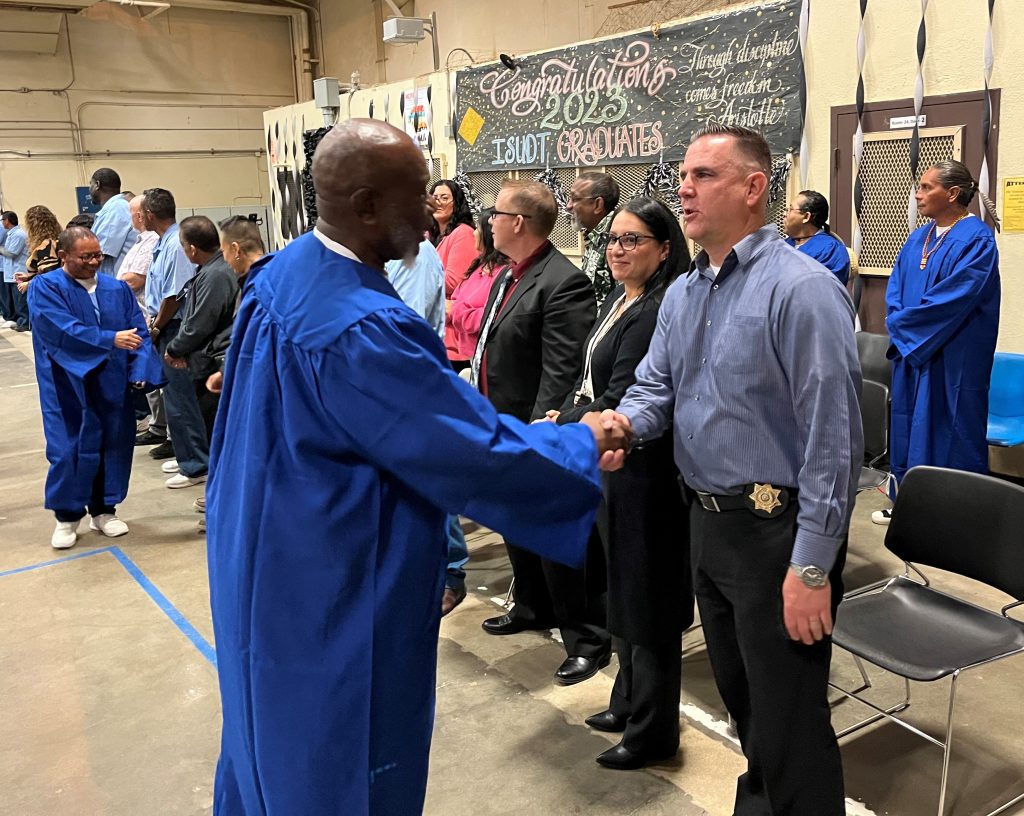 (A) Warden shakes hands with incarcerated at CTF ISUDT graduation