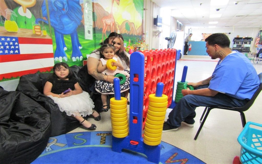 Thanksgiving event for visiting at Wasco State Prison-Reception Center with a family playing a game in the visiting room.
