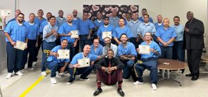 Pleasant Valley State Prison incarcerated men graduate Anti-Recidivism Coalition. The men are holding their certificates of completion.
