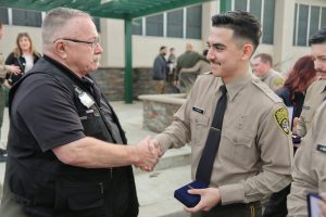 A chaplain shakes hands with a new correctional officer.