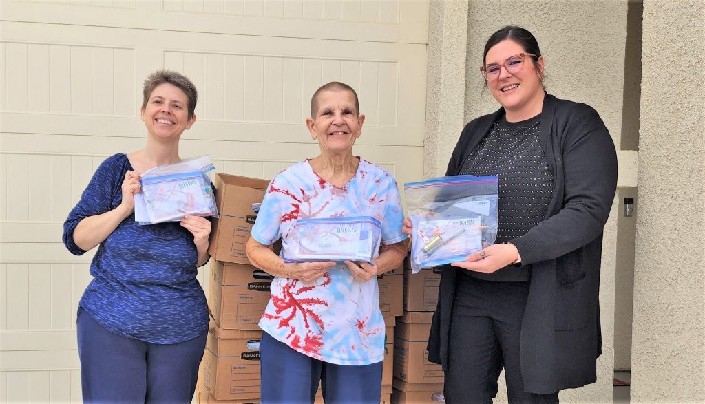 Three people holding gift bags to be donated to Central California Women's Facility.