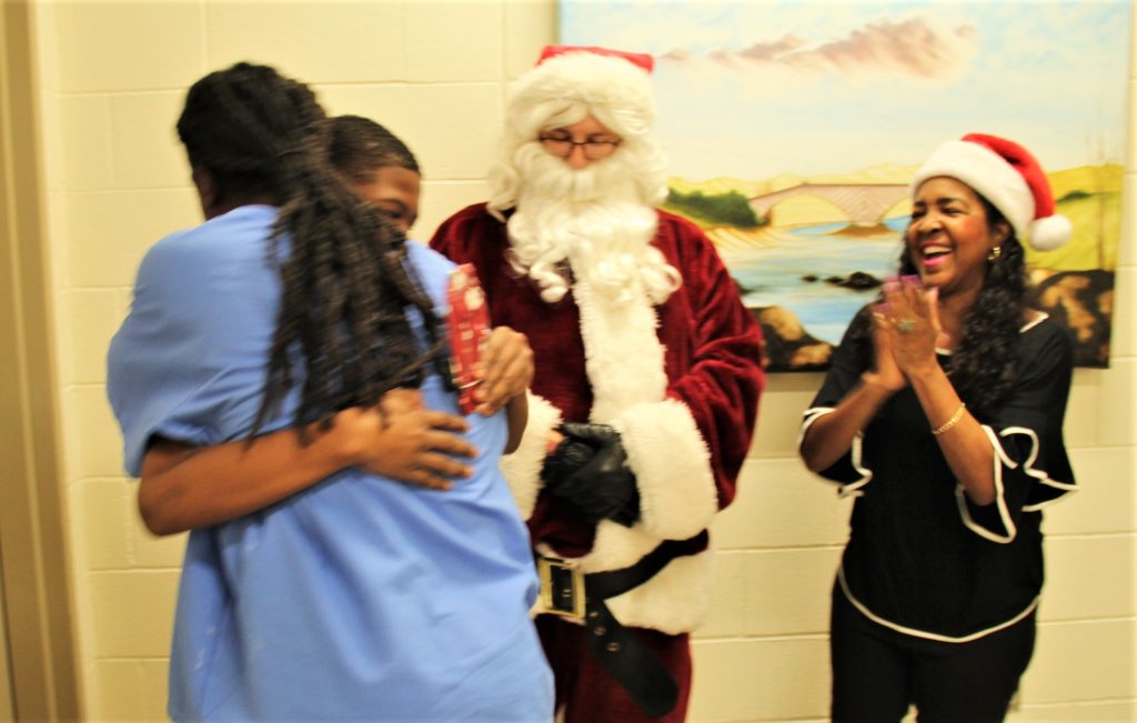 Two people hug while Santa and another woman look on.