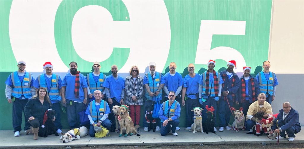 A group photo of incarcerated people, the prison warden, and dogs.