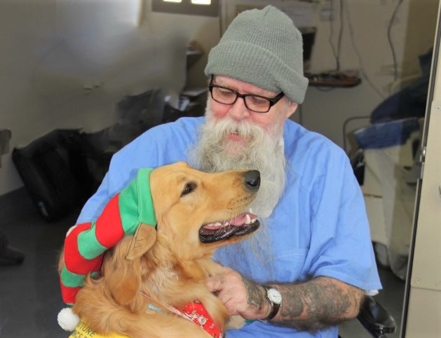 An incarcerated person pets a dog during a Canine Companions Puppy Parade. 