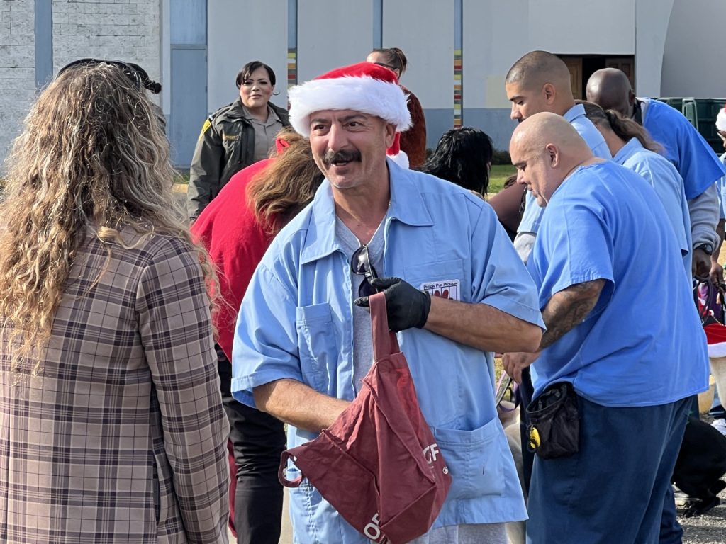 Incarcerated person digs into a bag to handout candy canes at a holiday parade.