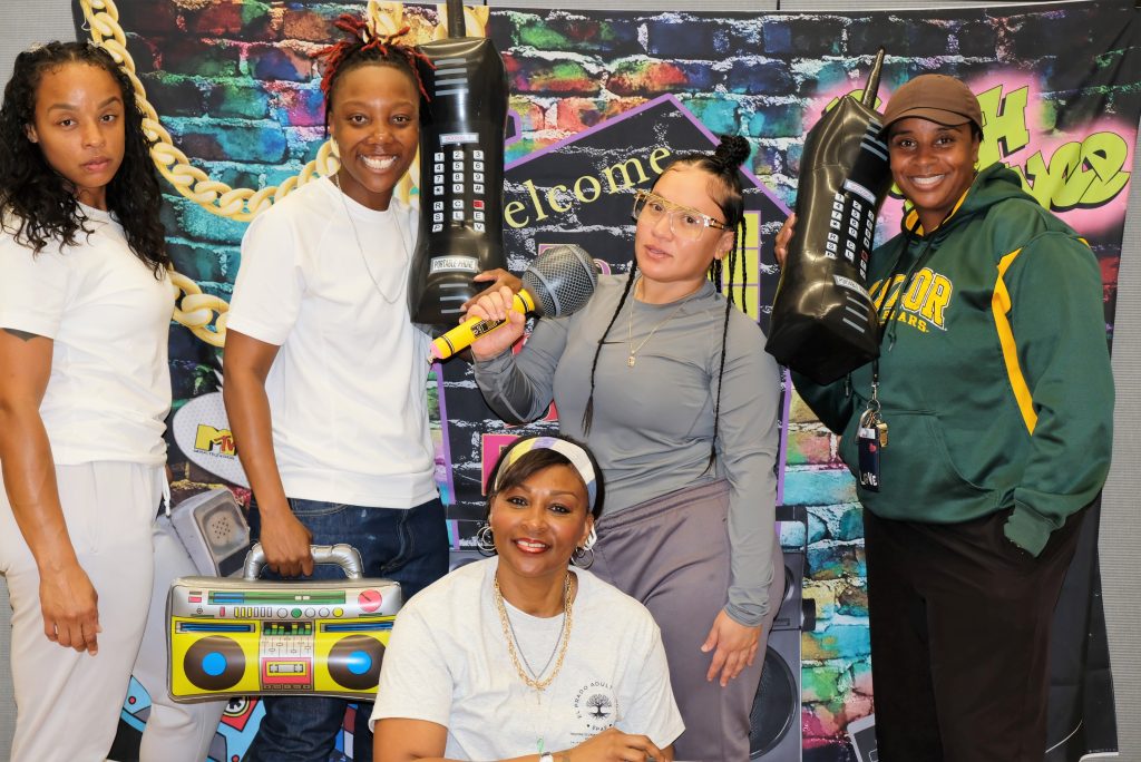 Staff and incarcerated people pose for photos at the women's adult school inside a California prison.