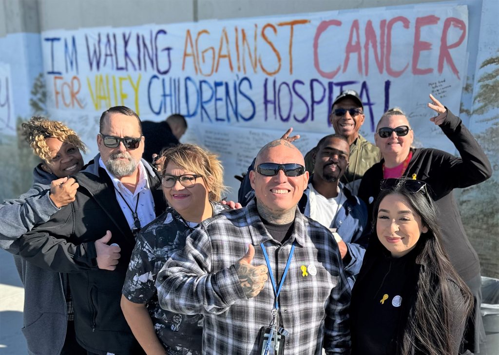 Staff members in front of a cancer walk banner.
