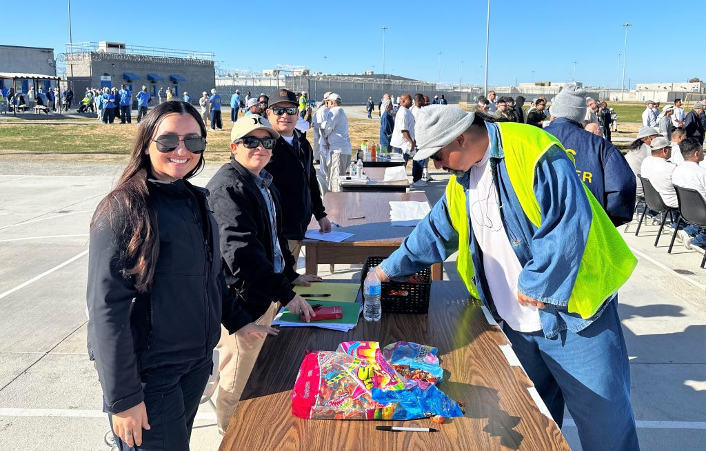 Speaking with an incarcerated person are three prison staff members.