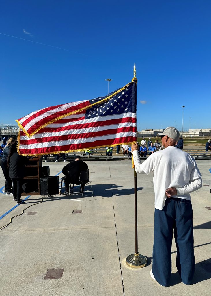 An incarcerated person holds a United States flag.