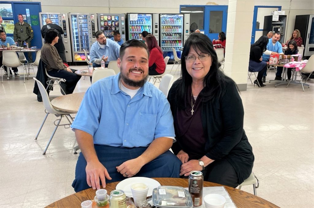 An incarcerated person and a visitor in the visiting room of a prison.