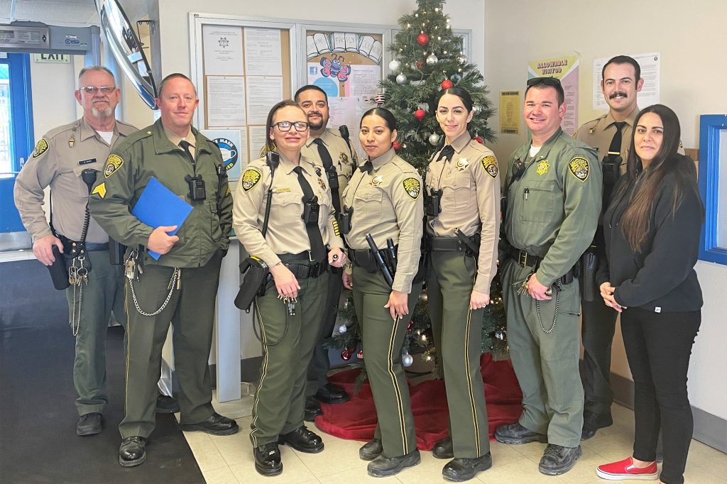 Corcoran prison staff in uniform, standing in front of a Christmas tree.