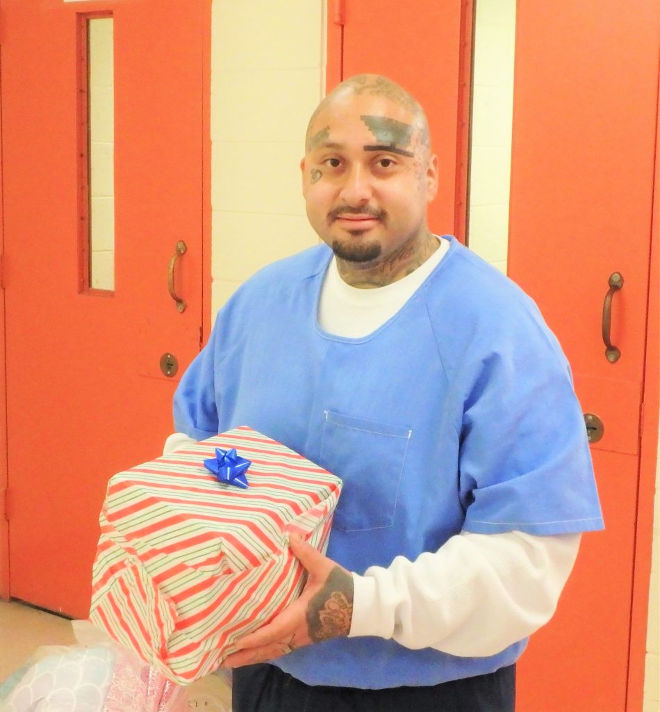 An incarcerated person holding a gift-wrapped present.