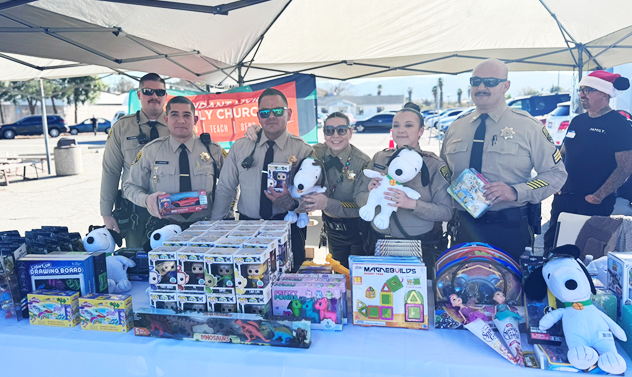 Correctional staff stand behind a table full of gifts for children.