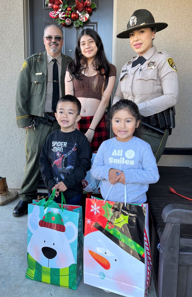 Two CDCR staff give gifts to three children.
