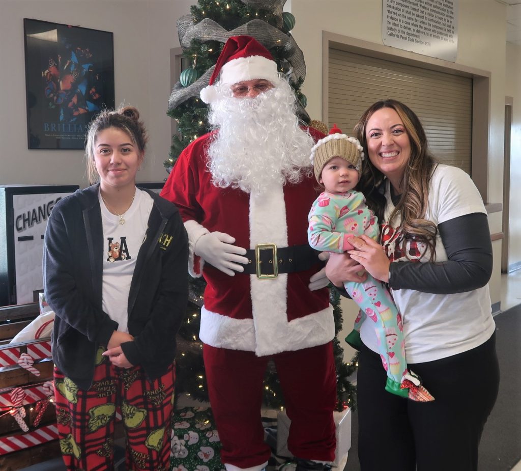Santa with two people and a baby inside a prison visiting room.
