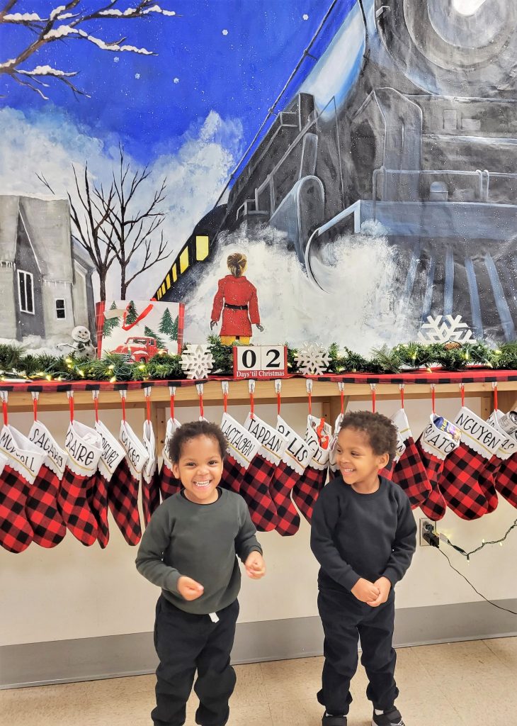 Two young children in front of a Polar Express Christmas backdrop.