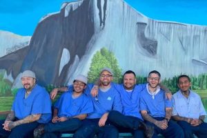 Incarcerated people sitting in front of a mural at Salinas Valley State Prison.