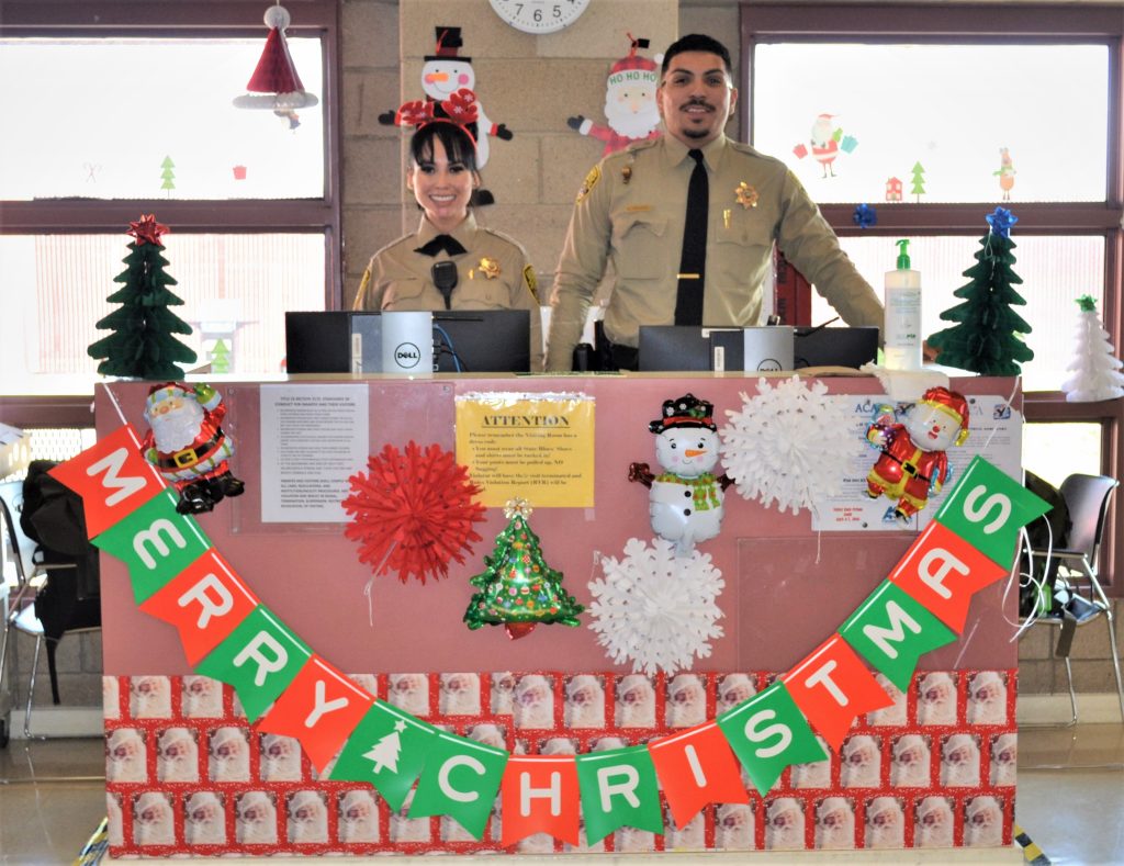 Visiting staff stand behind a counter with the words Merry Christmas hanging from the front along with other holiday decorations.