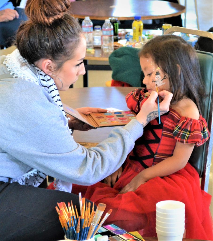 A young girl has her face painted at Valley State Prison.