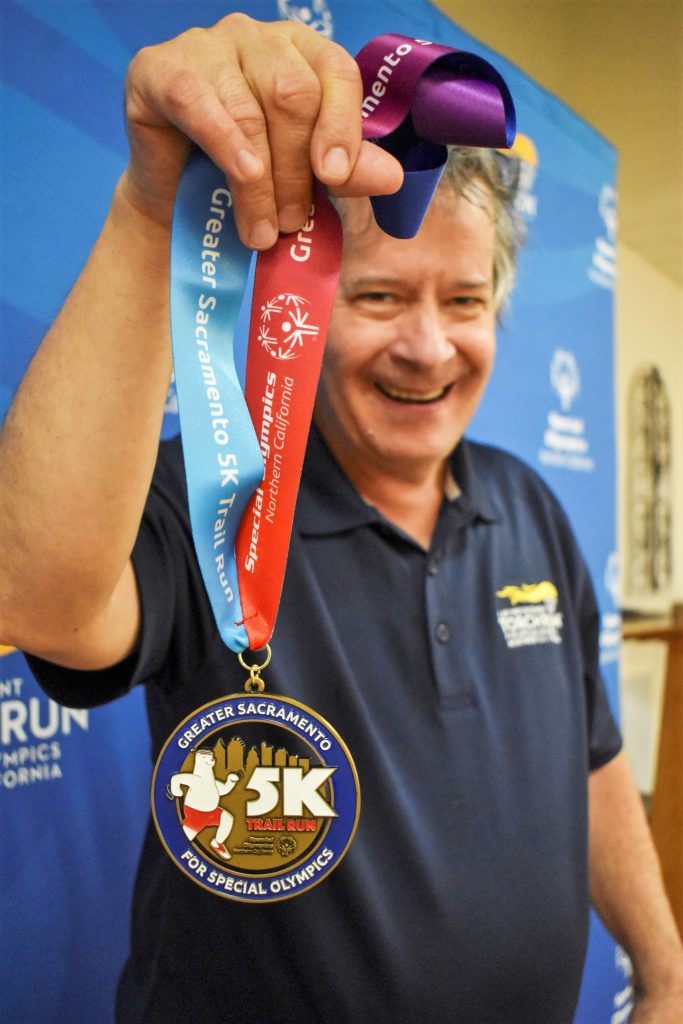 Special Olympics athlete holds a medal.