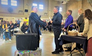 A graduate shakes hands with a Valley State Prison staff member.