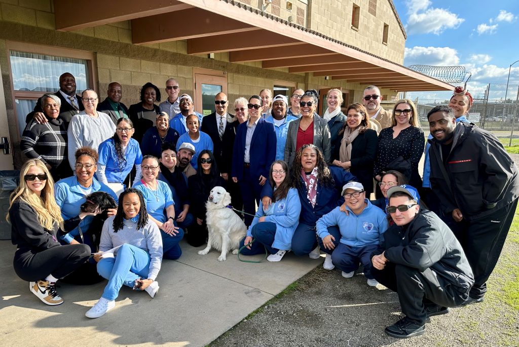 A group photo of CDCR staff and the Kardashian sisters at a California prison dog training program.