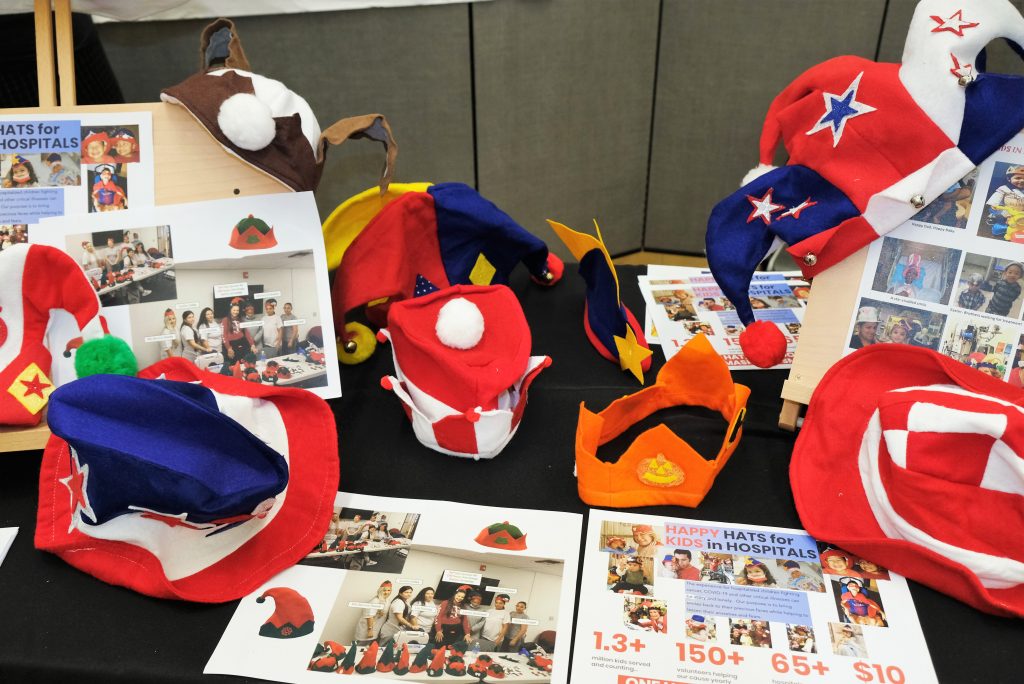 Hats for children in hospitals, with flyers, are displayed on tables.