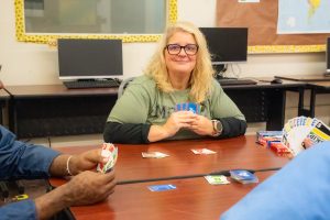 An educator plays cards with people at CMF at an education station.
