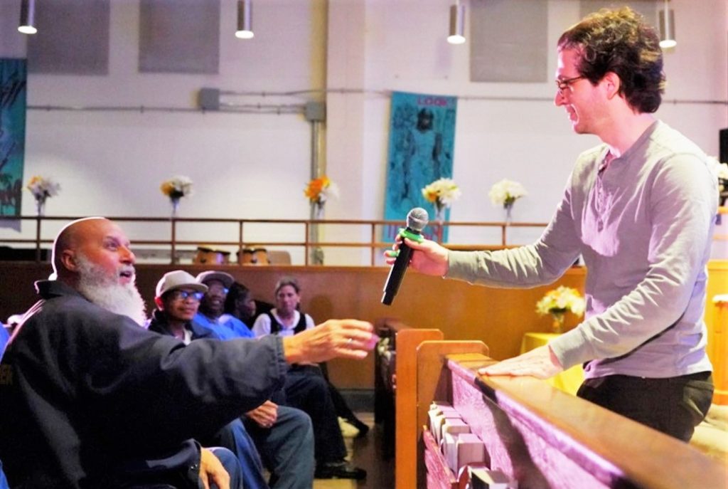 Matt Butler hands a microphone to an audience member at San Quentin Rehabilitation Center.
