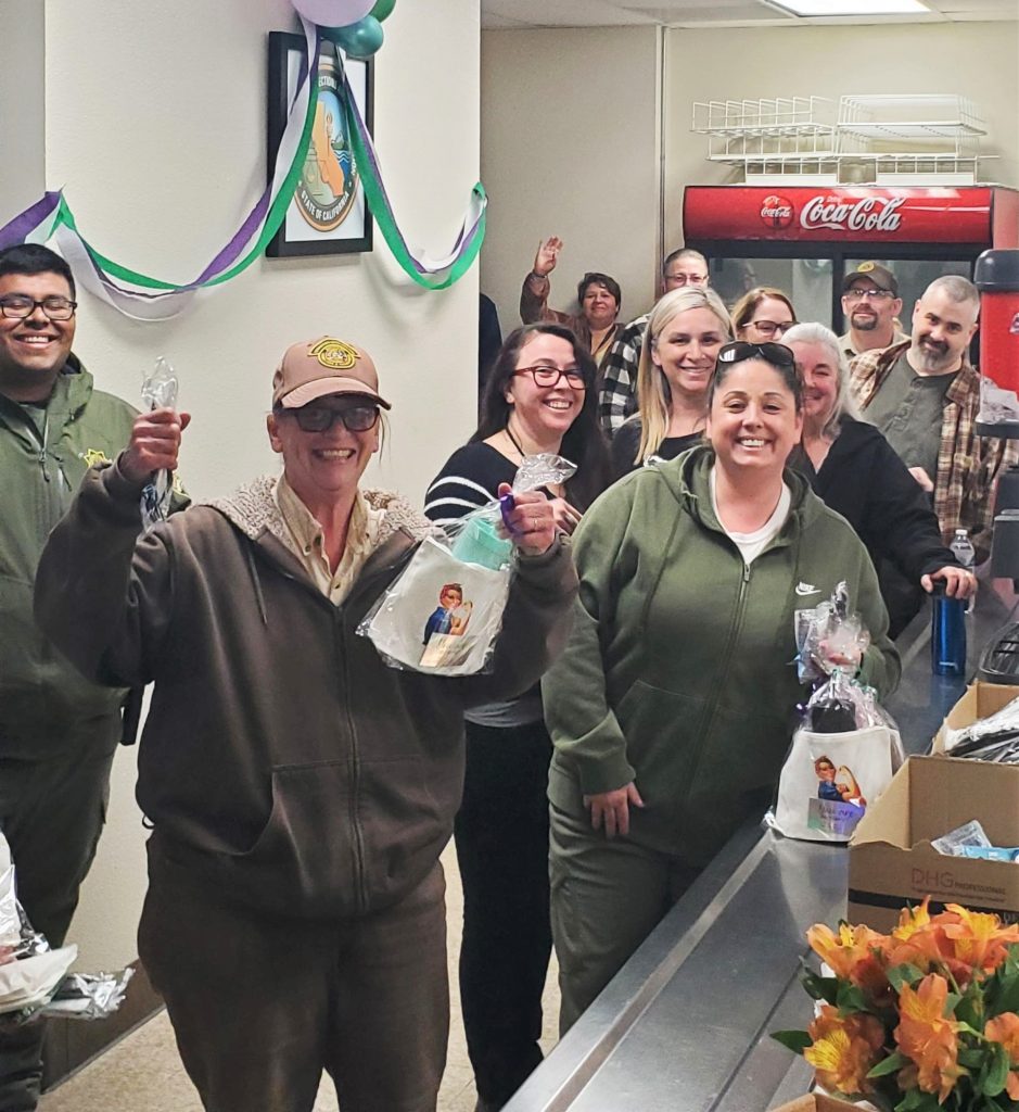 Staff smile and hold up gift bags.