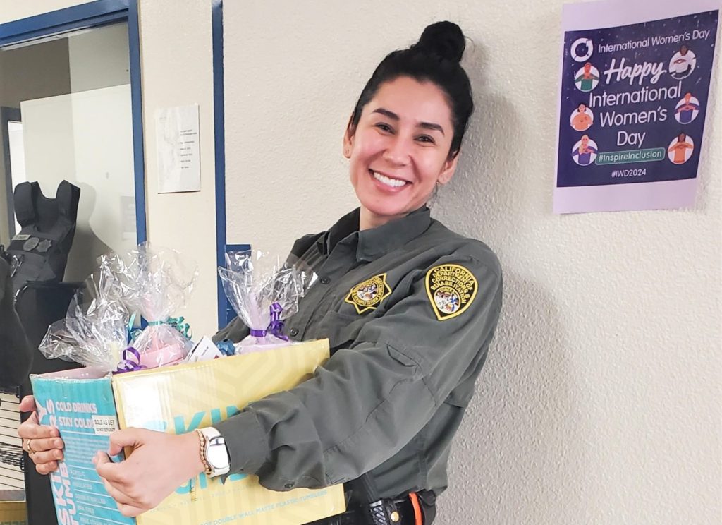 Woman carries a box of gift bags for the Pelican Bay State Prison International Women's Day event.