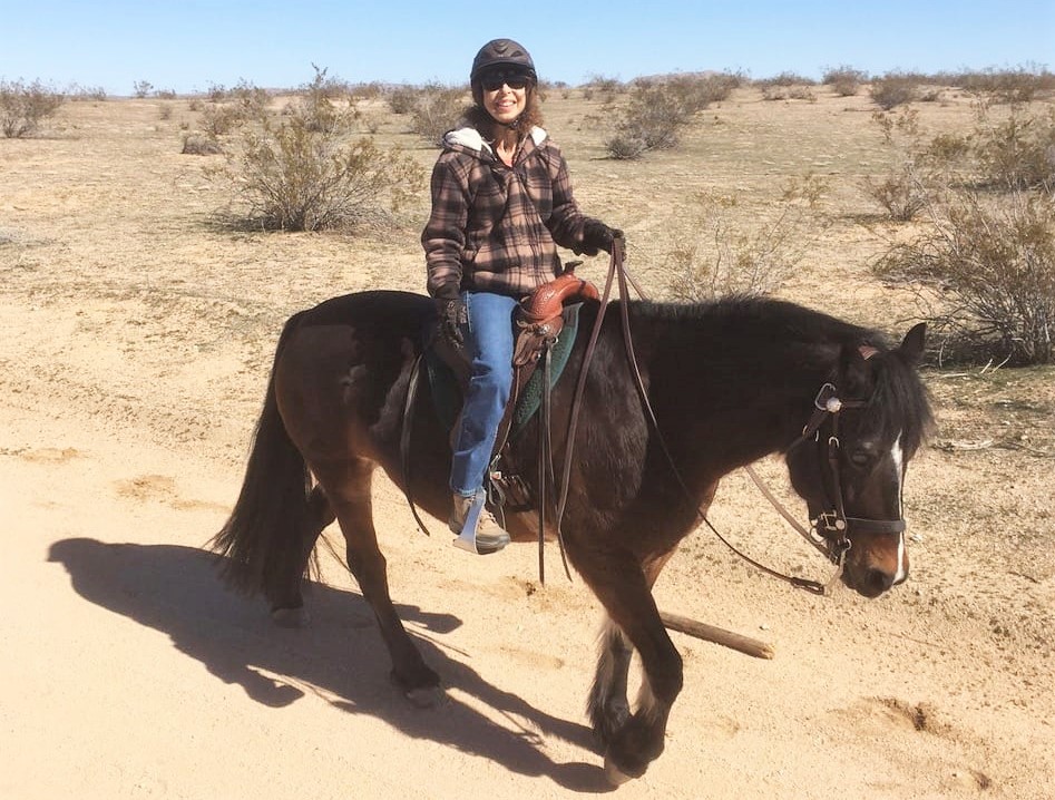 Renee Baust on horseback with the desert in the background.