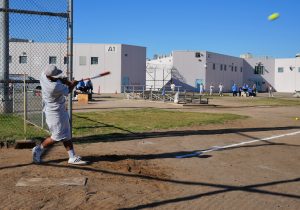 Centinela State Prison Home Run Derby with an incarcerated person hitting balls with a baseball bat.