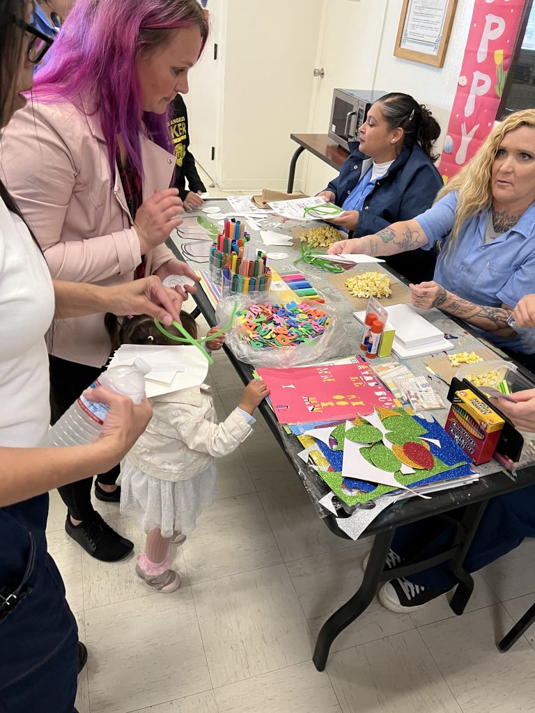 Incarcerated people at a craft table for visiting kids.