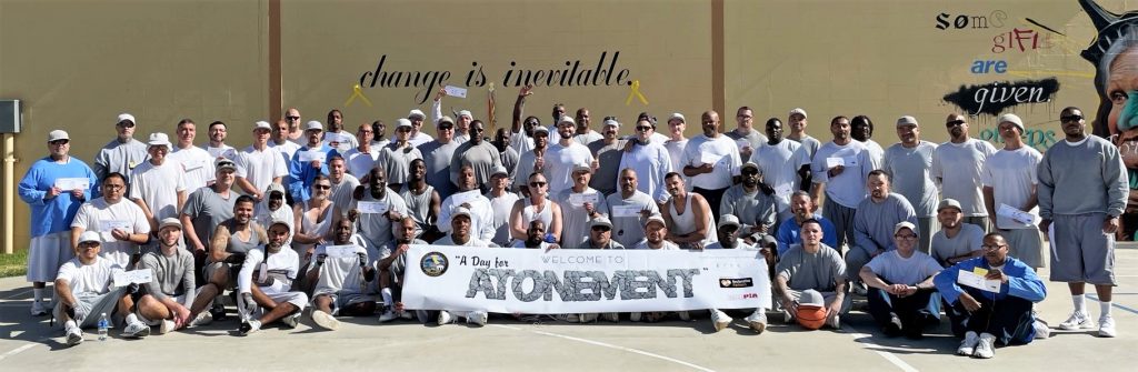 A group of incarcerated people at California Men's Colony hold a banner that reads "A Day for Atonement."