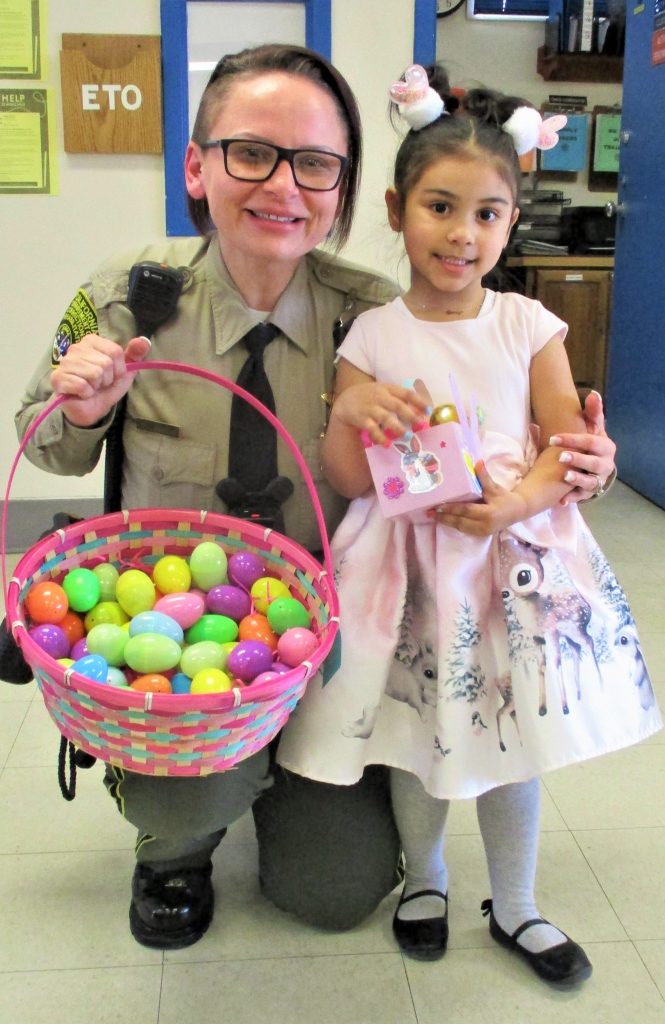 A correctional officer poses for a photo with a young girl wearing an Easter dress.