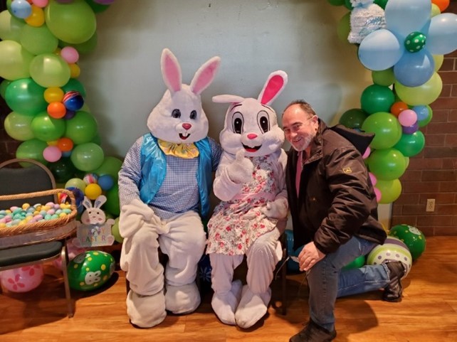 Parole agent kneeling beside Easter bunnies.