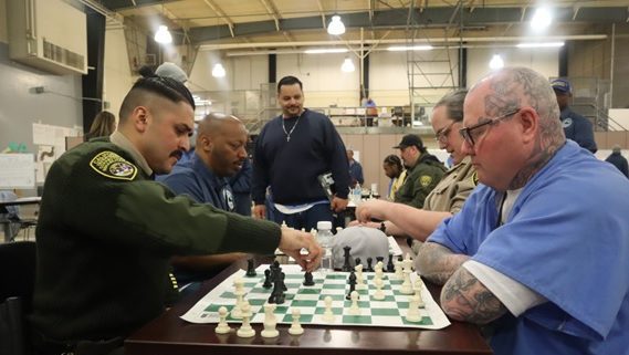 A correctional officer plays chess against an incarcerated player.