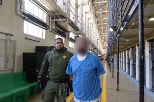 Condemned inmate transfer program with officer escorting an inmate out of San Quentin Rehabilitation Center.