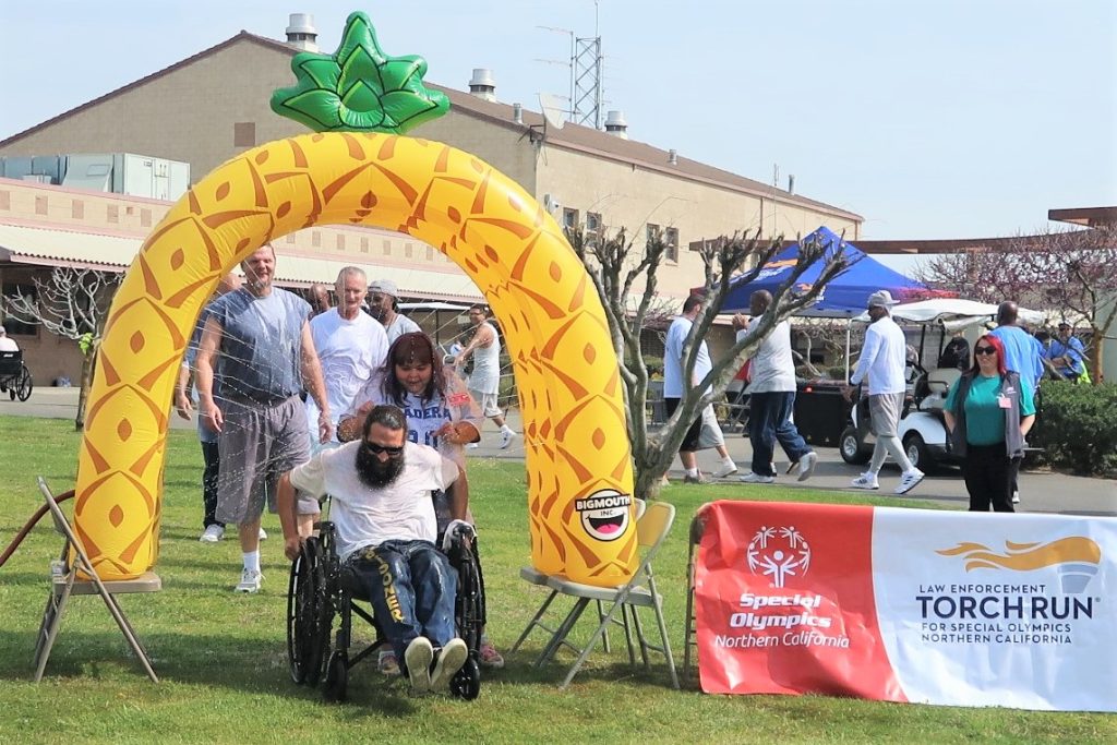 Incarcerated person in a wheelchair rolls through a water soaker as a fundraiser.