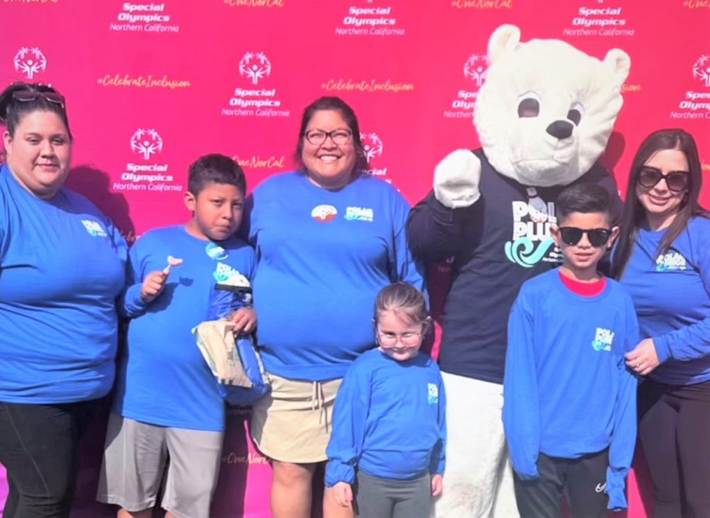 Three Valley State Prison staff members wearing blue t-shirts at a special event.