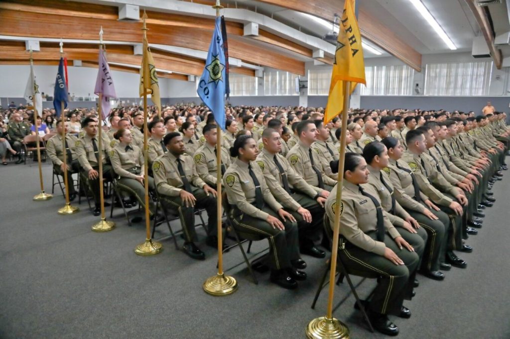 A group photo of the 207 new correctional officers seated in a large auditorium for their graduation from the academy.