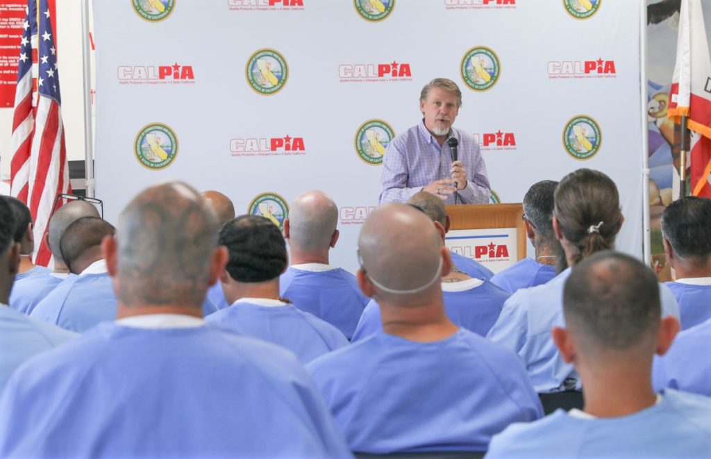 The general manager of CALPIA speaks at a graduation ceremony.